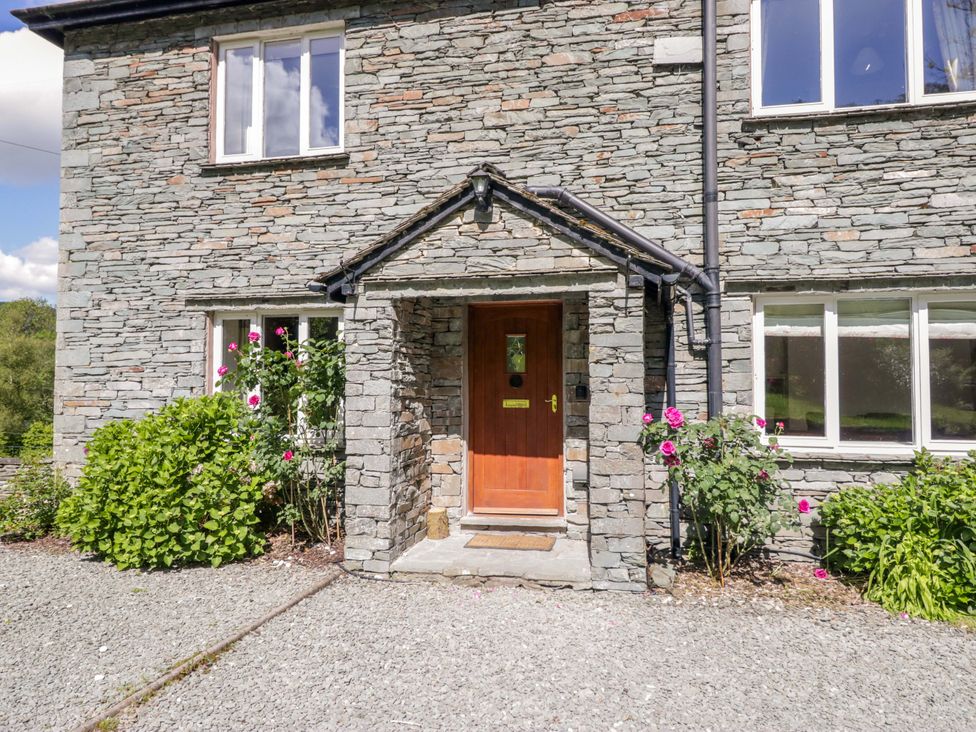 A stone exterior with a front door and garden plants at Elterwater Lodge Elterwater