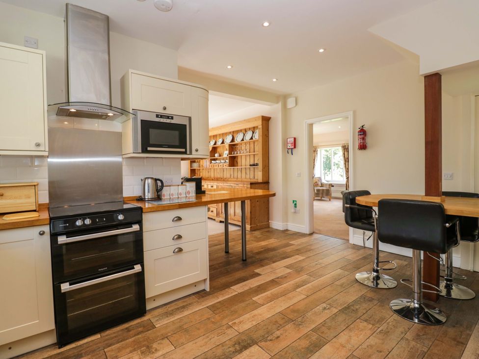 A kitchen with an oven, microwave and bar stools at Elterwater Lodge in Elterwater