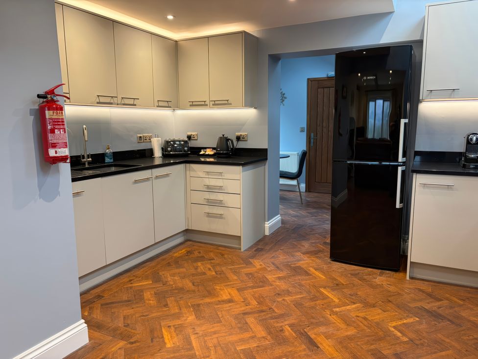 A kitchen with cabinets, sink, and appliances at Dancing Beck Cottage in Millbeck