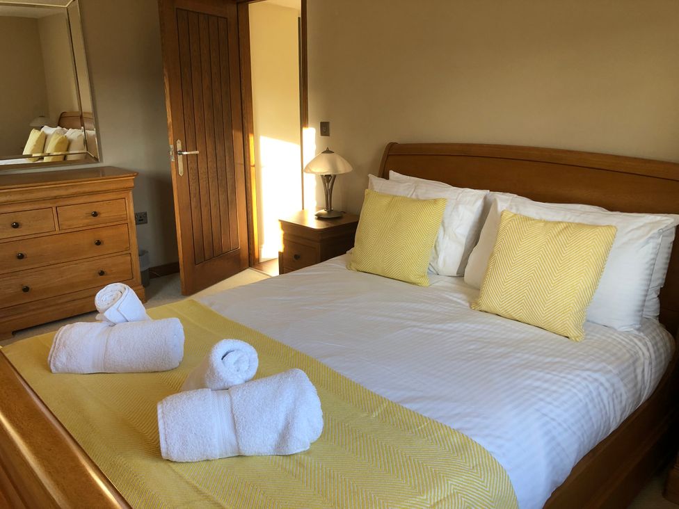 A bedroom with a bed, dresser, and door at Dancing Beck Cottage in Millbeck