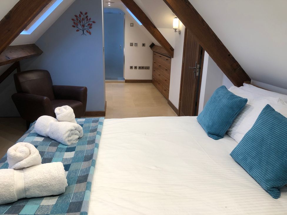 A bedroom with a bed and chair at Dancing Beck Cottage in Millbeck