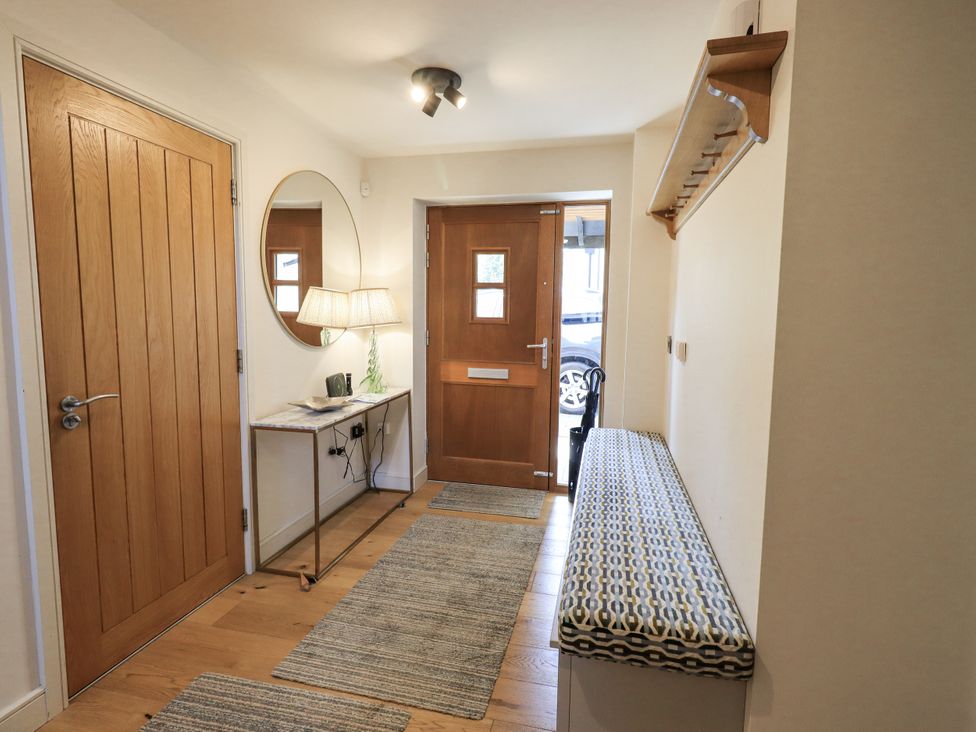 A hallway with a mirror, lamp, table and coat rack at No 7, Ambleside