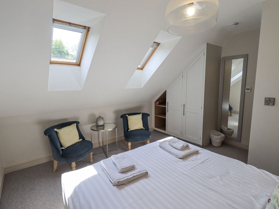 A bedroom with a bed, two chairs, and a mirror at No 7 in Ambleside