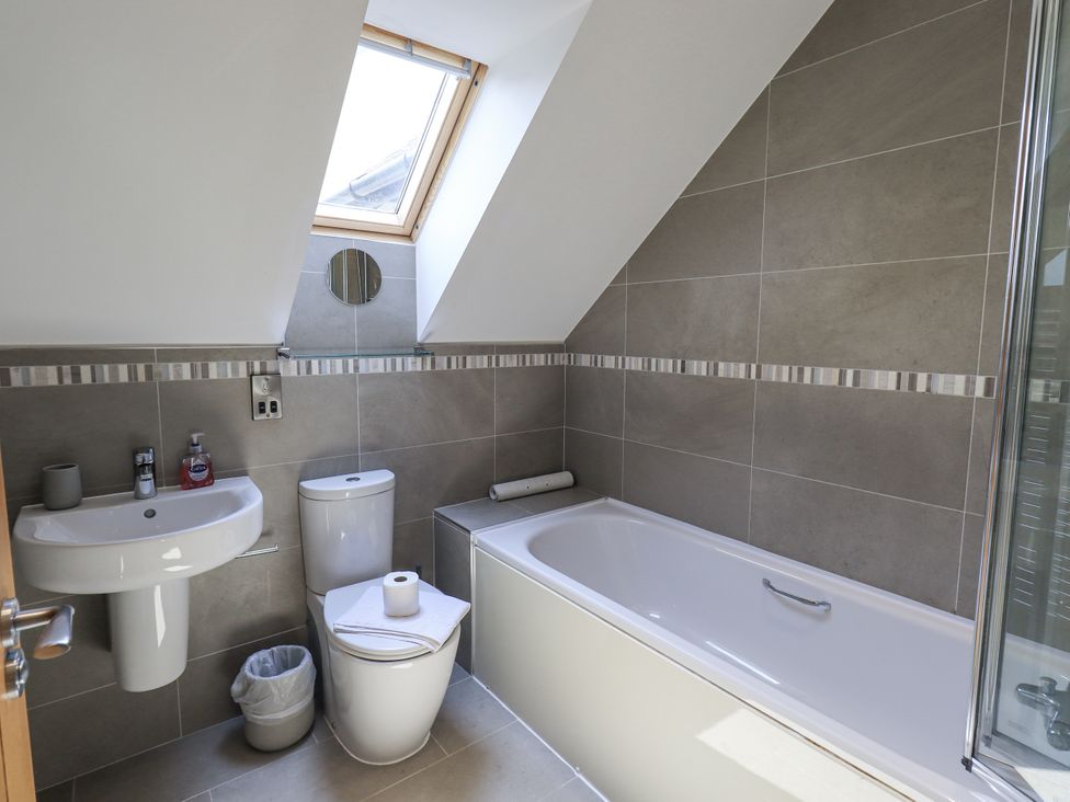 A bathroom with a bath tub, sink, and toilet at No 7 Ambleside
