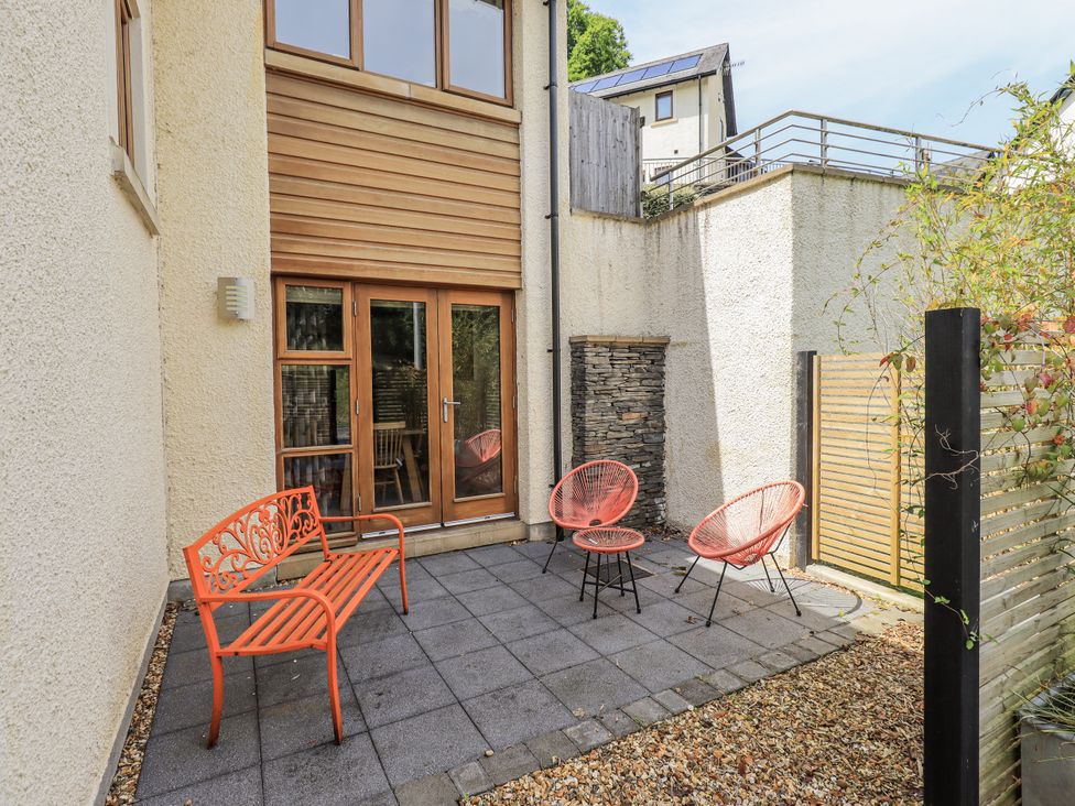 An outdoor patio with red chairs and a stone wall at No 7 Ambleside