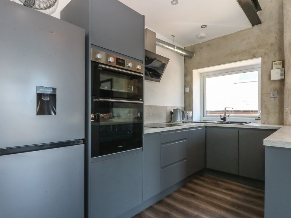 A kitchen with refrigerator, oven, sink and window at Sea View Llandudno