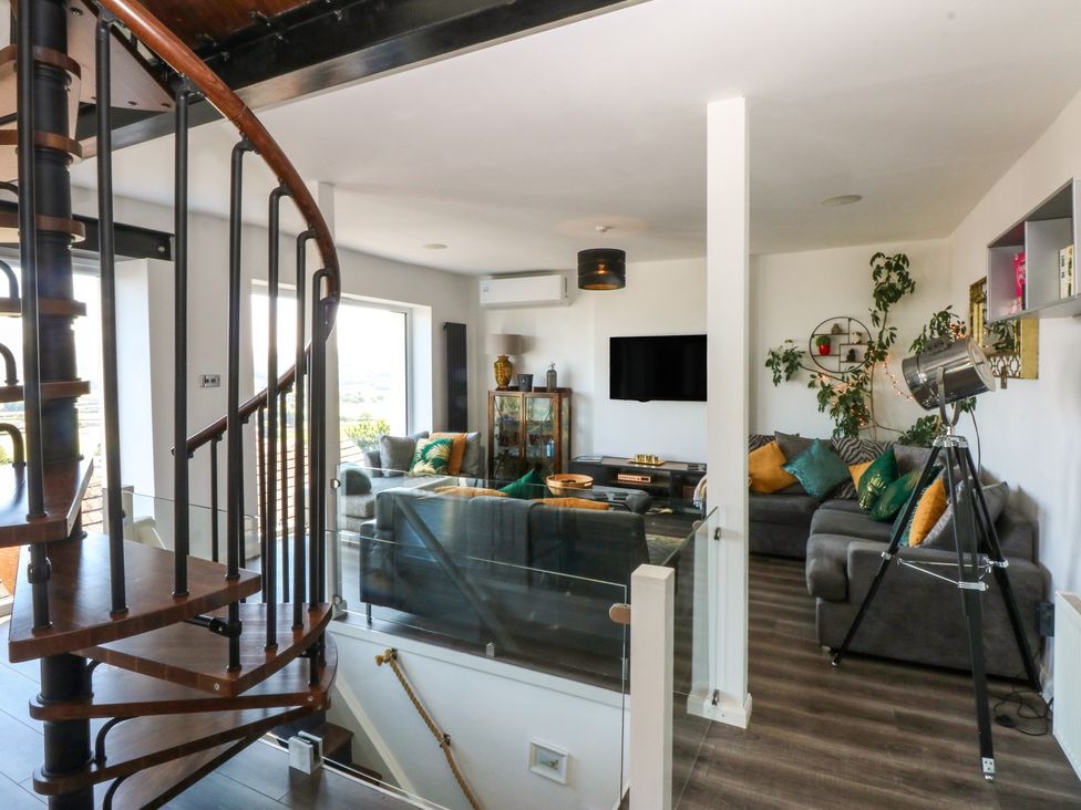 A living room with a spiral staircase and a tv at Sea View in Llandudno
