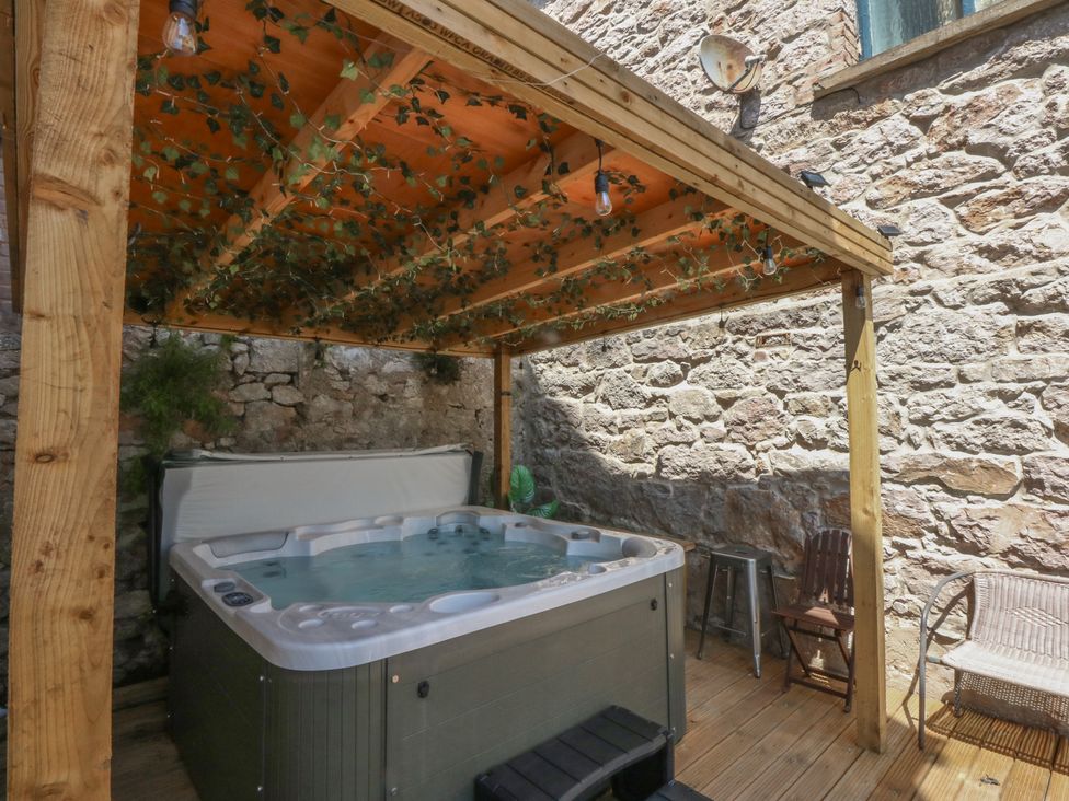 An outdoor area with a hot tub under a wooden structure at Sea View in Llandudno