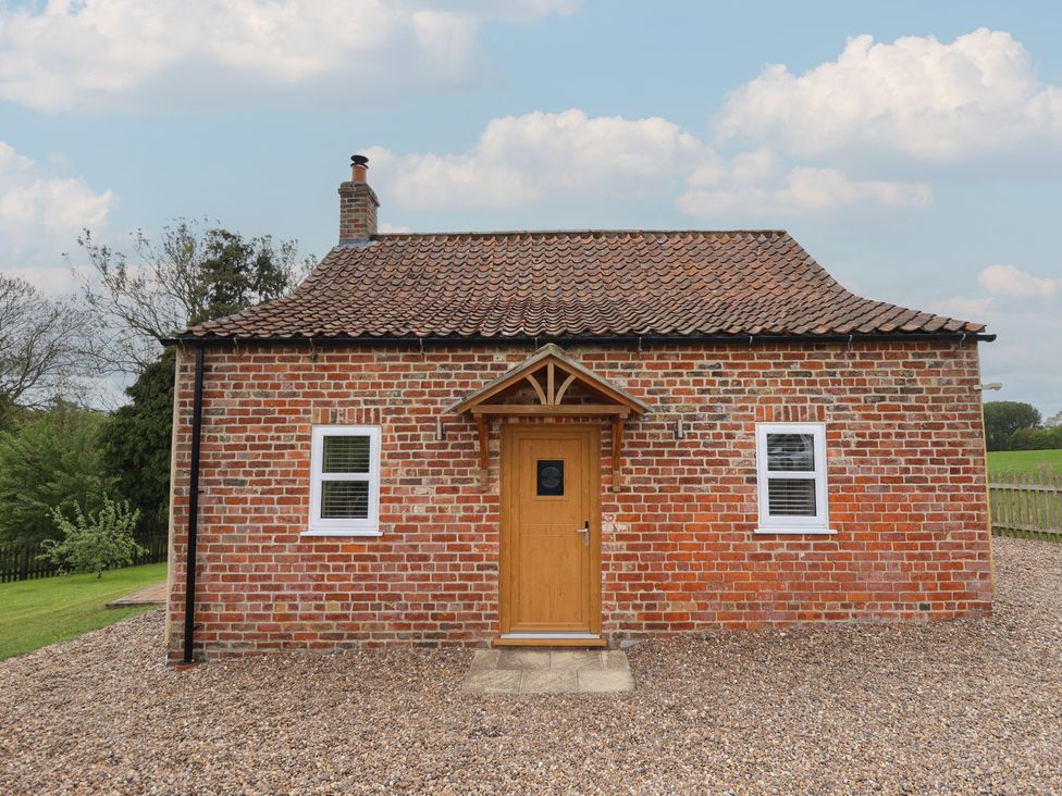 A cottage with a brick exterior and a wooden door at Shepherd's Cottage Claythorpe near Alford