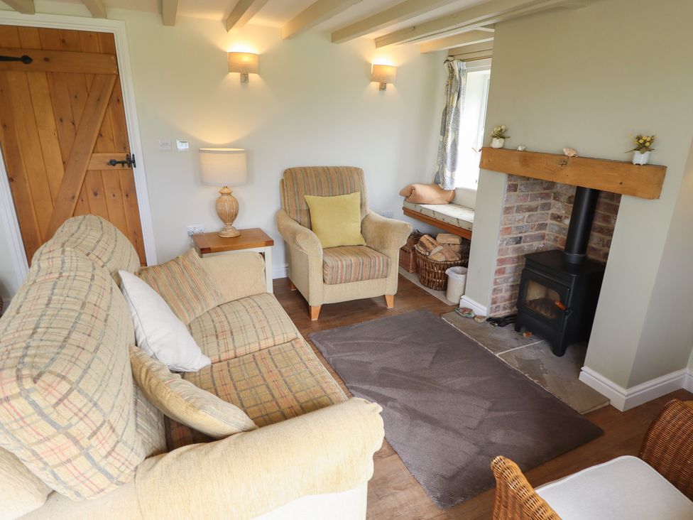 A living room with a sofa and armchair near a fireplace at Shepherd's Cottage in Claythorpe near Alford