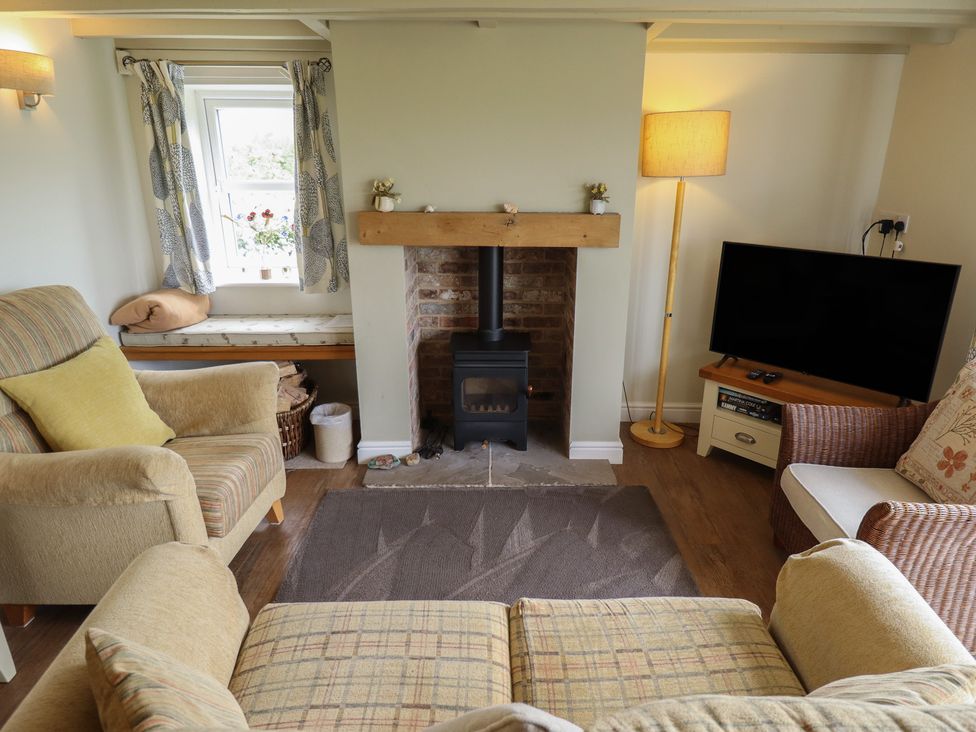 A living room with a fireplace and sofa at Shepherd's Cottage in Claythorpe near Alford
