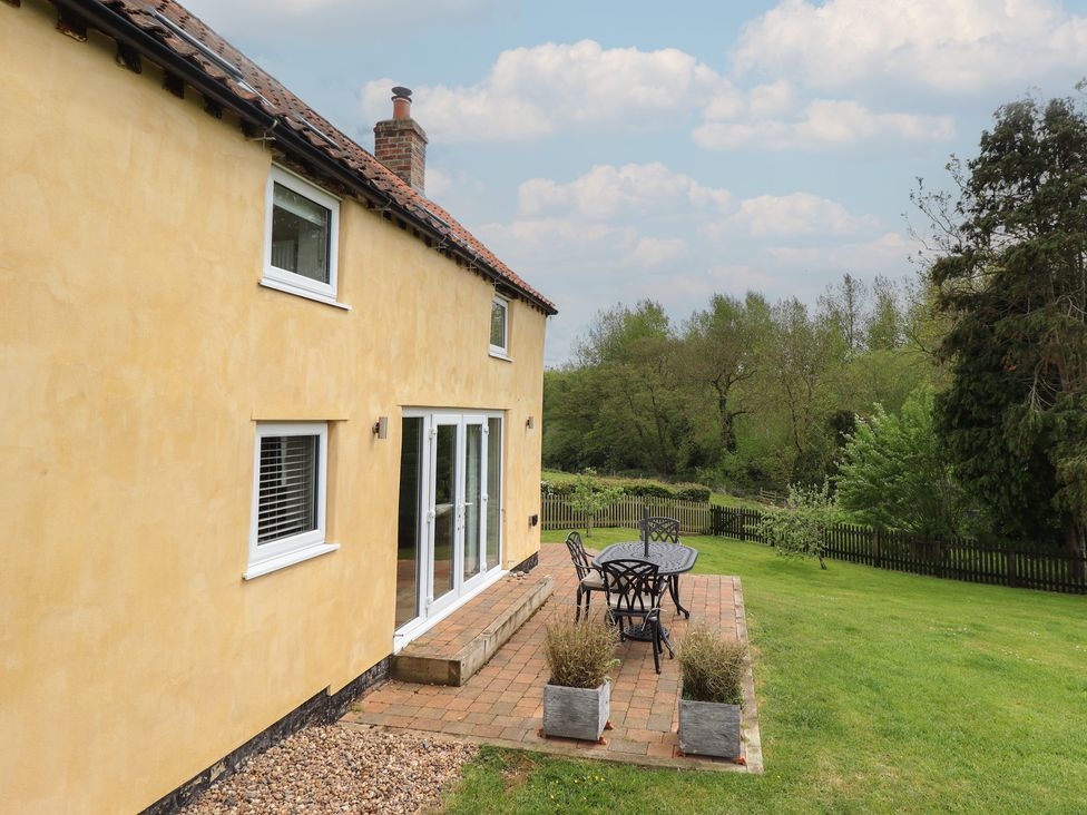 A house with windows and a patio table and chairs at Shepherd's Cottage in Claythorpe near Alford