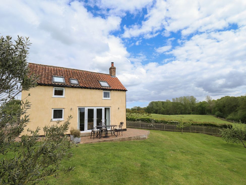 A house with a patio and table in an outdoor area at Shepherd's Cottage in Claythorpe near Alford