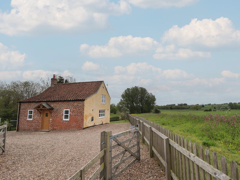 A house with a gravel driveway and a fence at Shepherd's Cottage in Claythorpe near Alford