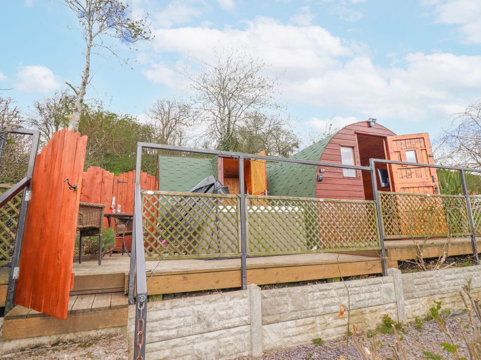An outdoor area with a wooden deck and a green structure at The Rhiw in Llanfair Caereinion
