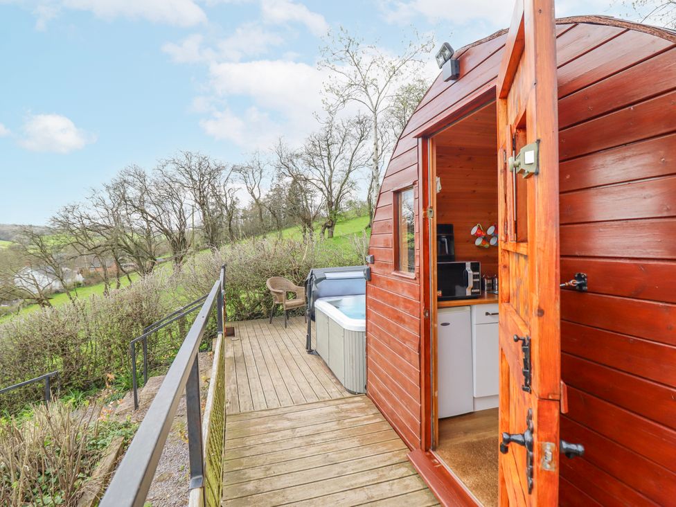 An outdoor area with a hot tub and wooden door at The Rhiw in Llanfair Caereinion