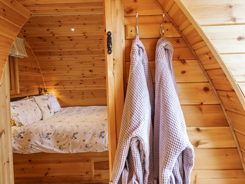 A bedroom with a bed and robes hanging at The Rhiw in Llanfair Caereinion