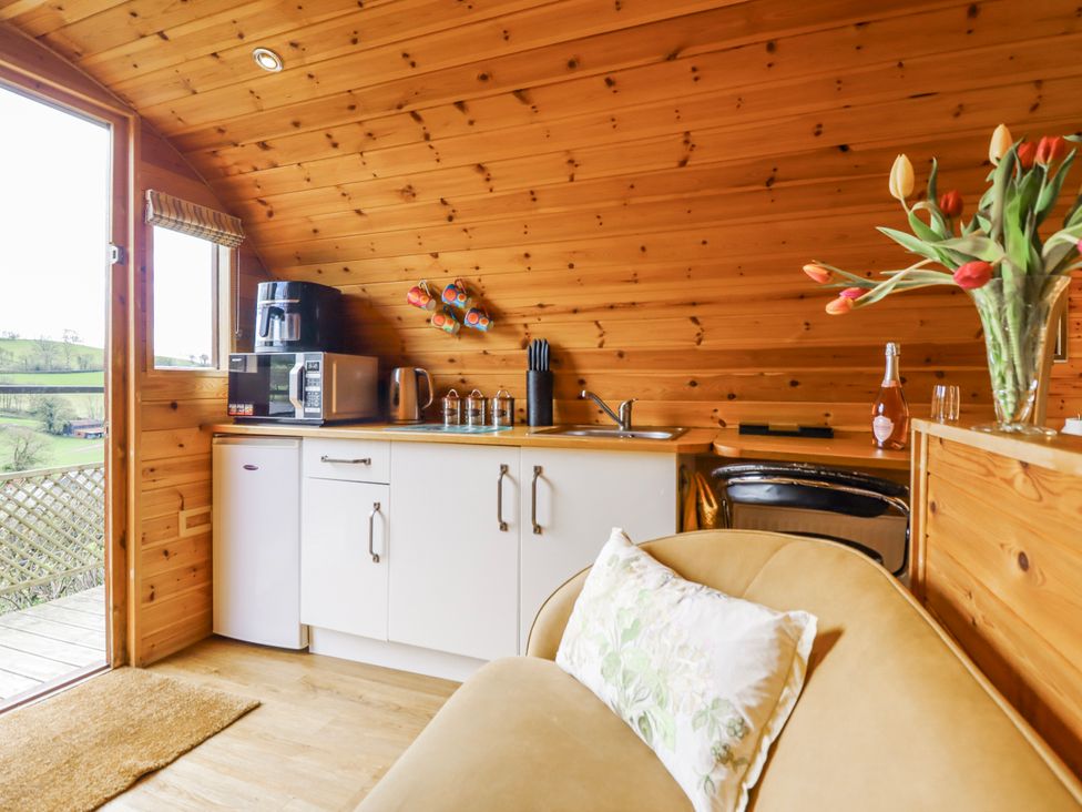 A kitchen area with appliances and a sofa at The Rhiw in Llanfair Caereinion