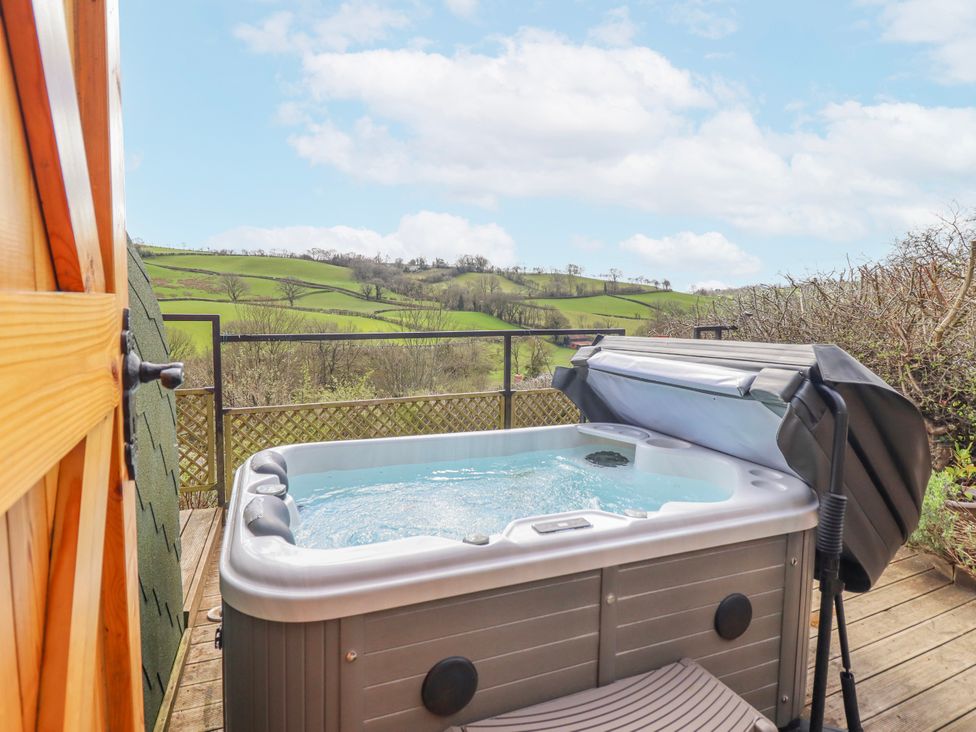 An outdoor area with a hot tub and a view of the landscape at The Rhiw in Llanfair Caereinion