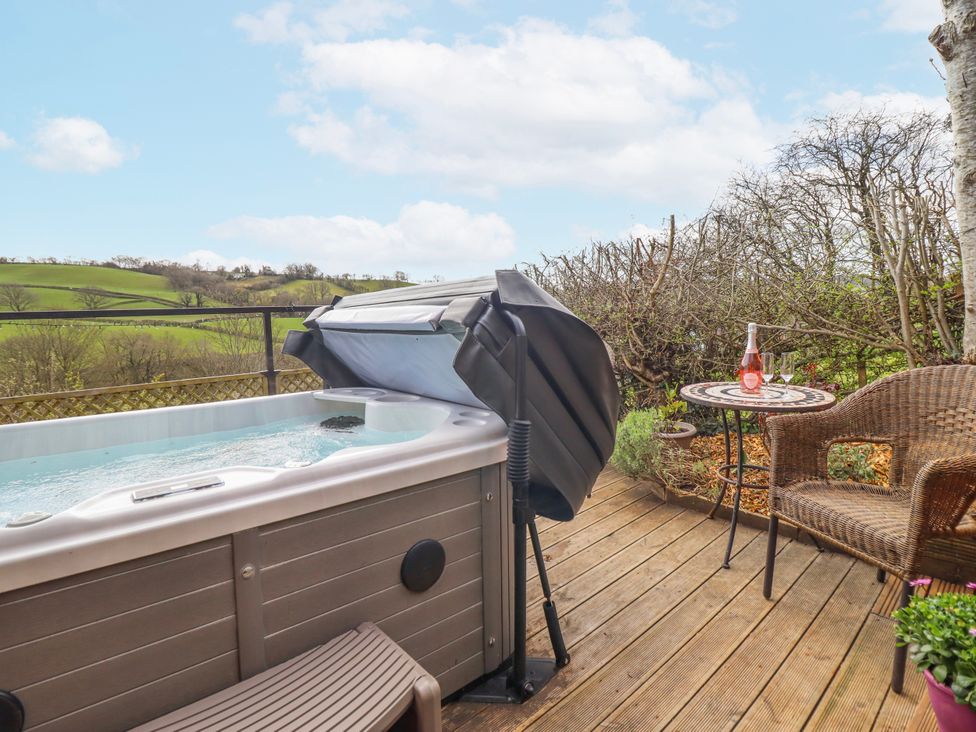 An outdoor seating area with a hot tub and a table at The Rhiw in Llanfair Caereinion