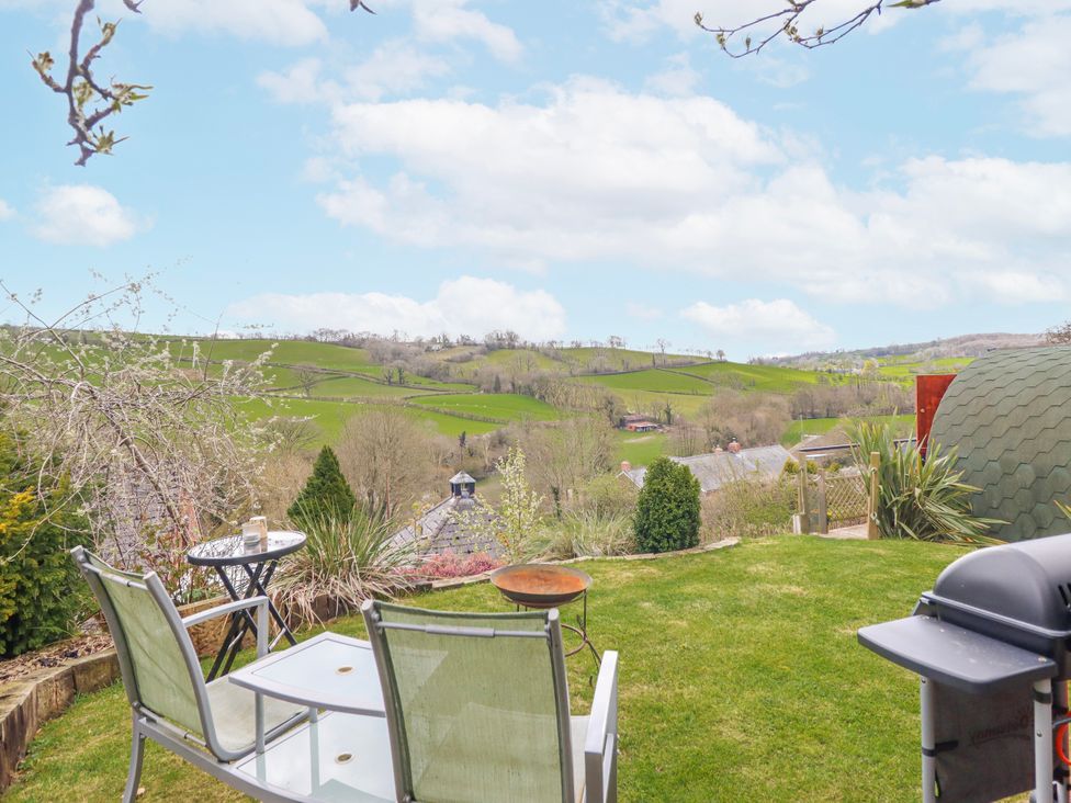 A garden with chairs and a table overlooking hills at The Rhiw in Llanfair Caereinion
