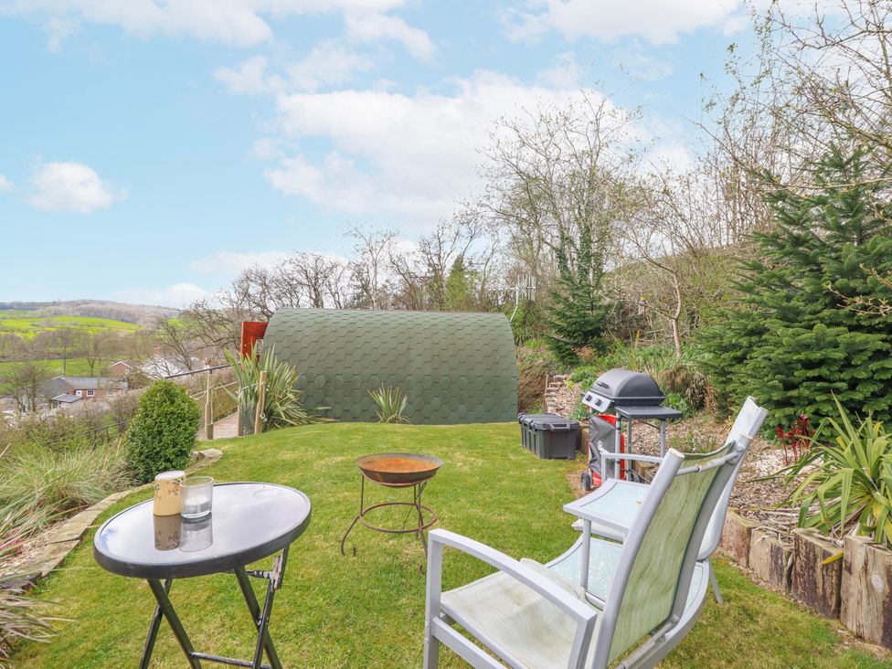 A garden with a green shed and seating area at The Rhiw in Llanfair Caereinion