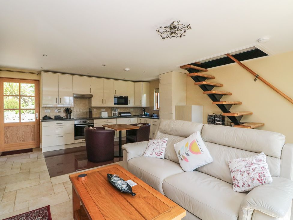 A living room with kitchen appliances and seating area at Ettrick Cottage Rothesay