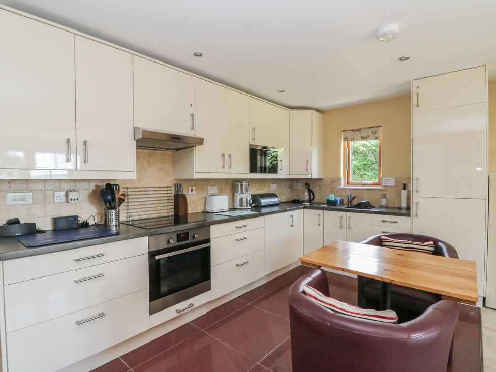 A kitchen with cabinets and a table at Ettrick Cottage in Rothesay