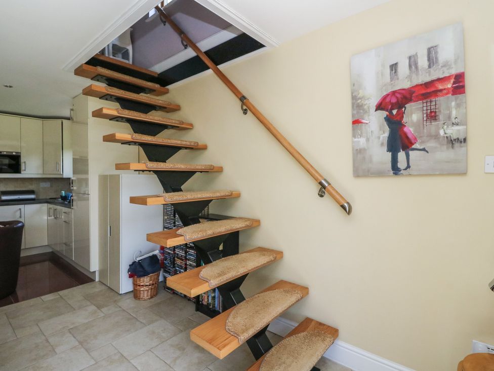 A staircase with wall art and a kitchen area at Ettrick Cottage Rothesay
