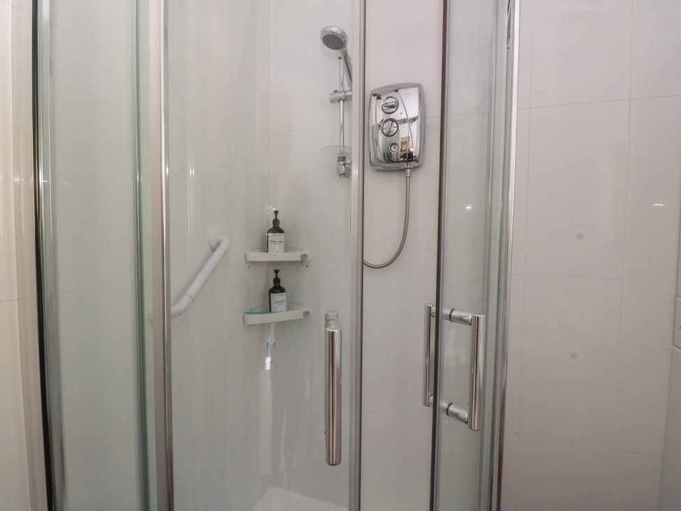 A shower with a shelf and soap dispenser at Ettrick Cottage in Rothesay