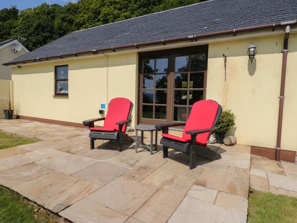 An outdoor seating area with red chairs and a table at Ettrick Cottage Rothesay