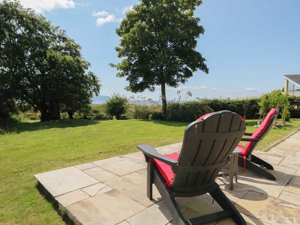 An outdoor area with deck chairs and a tree at Ettrick Cottage Rothesay