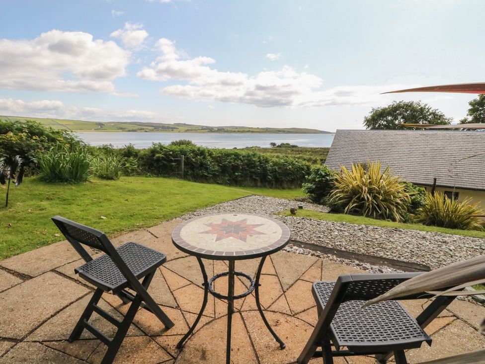 A garden with table and chairs overlooking a water view at Ettrick Cottage in Rothesay