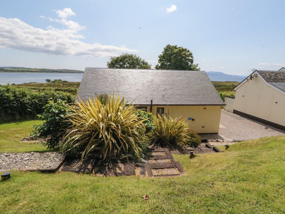 An exterior view of a house with garden and water in the background at Ettrick Cottage in Rothesay