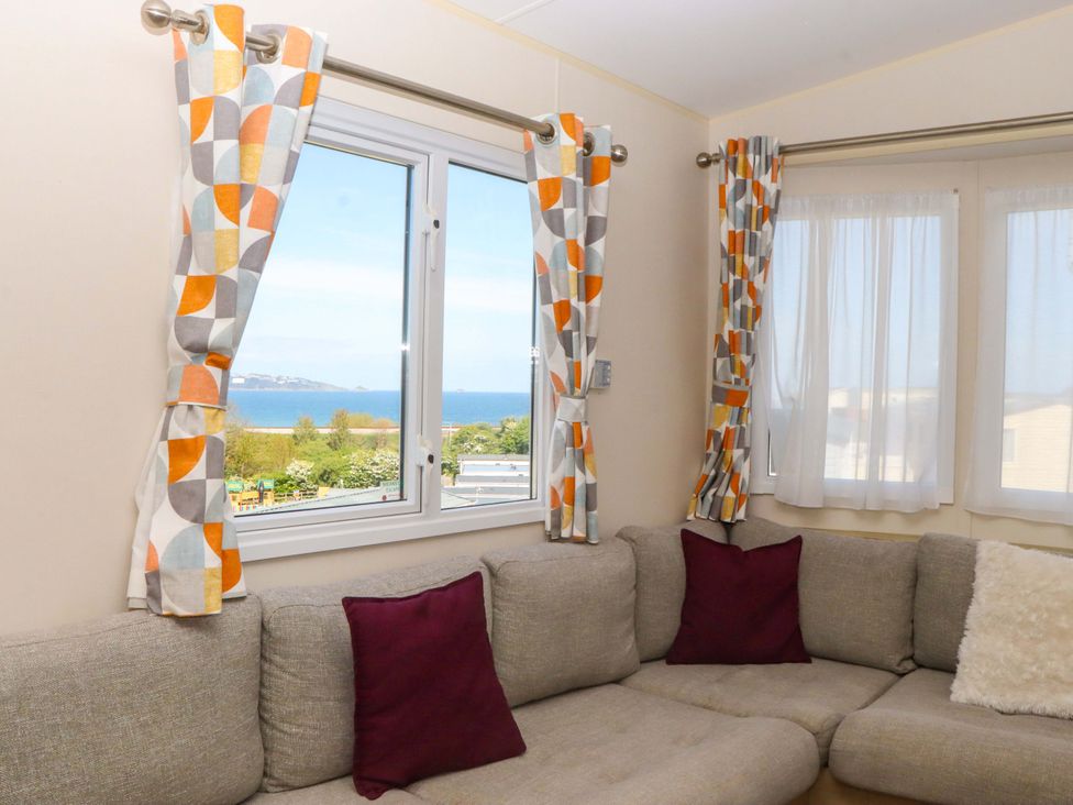 A living room with a sofa and curtains overlooking a view at 213 Seaview Caravan