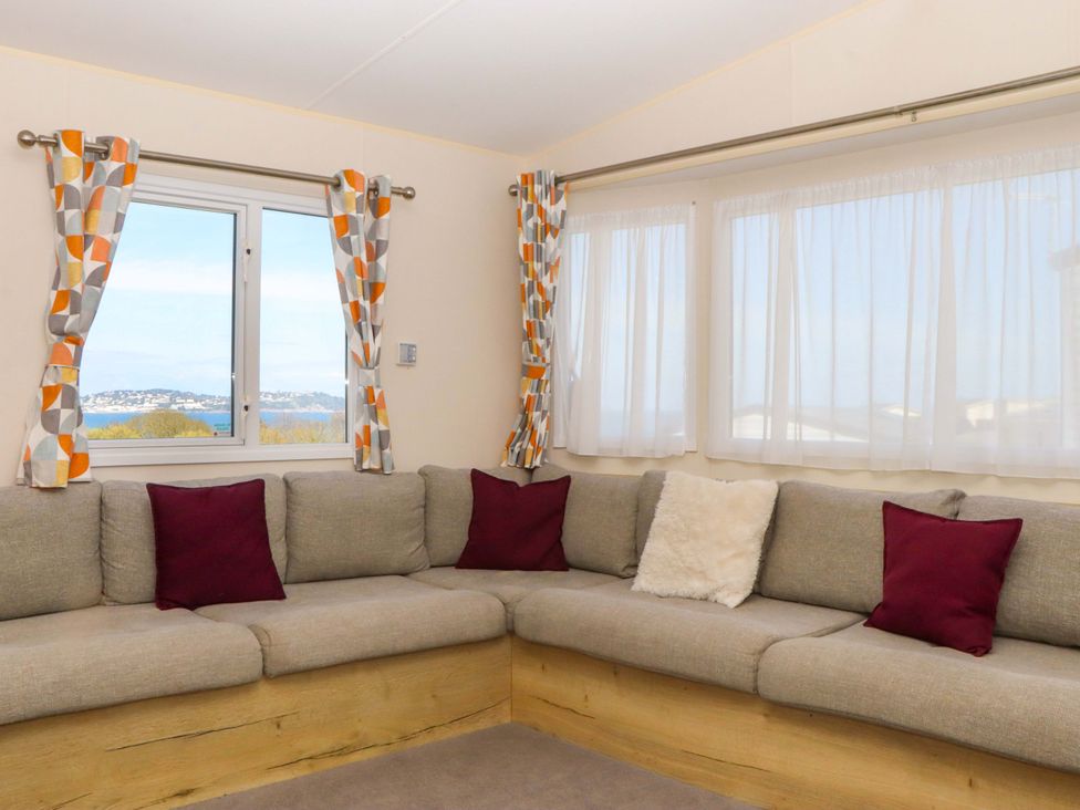 A living room with a sectional sofa and windows at 213 Seaview Caravan
