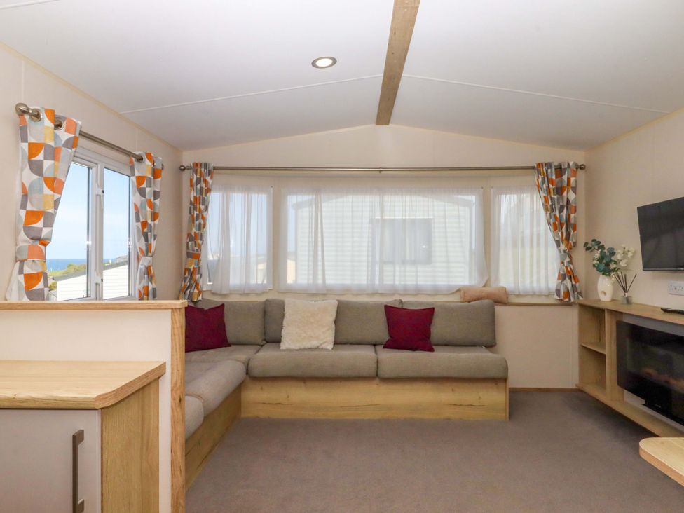 A living room with a sofa and television at 213 Seaview Caravan