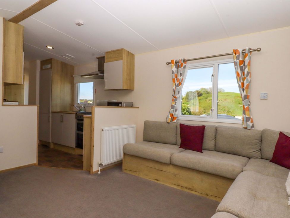 A living room with a sofa and kitchen area at 213 Seaview Caravan 