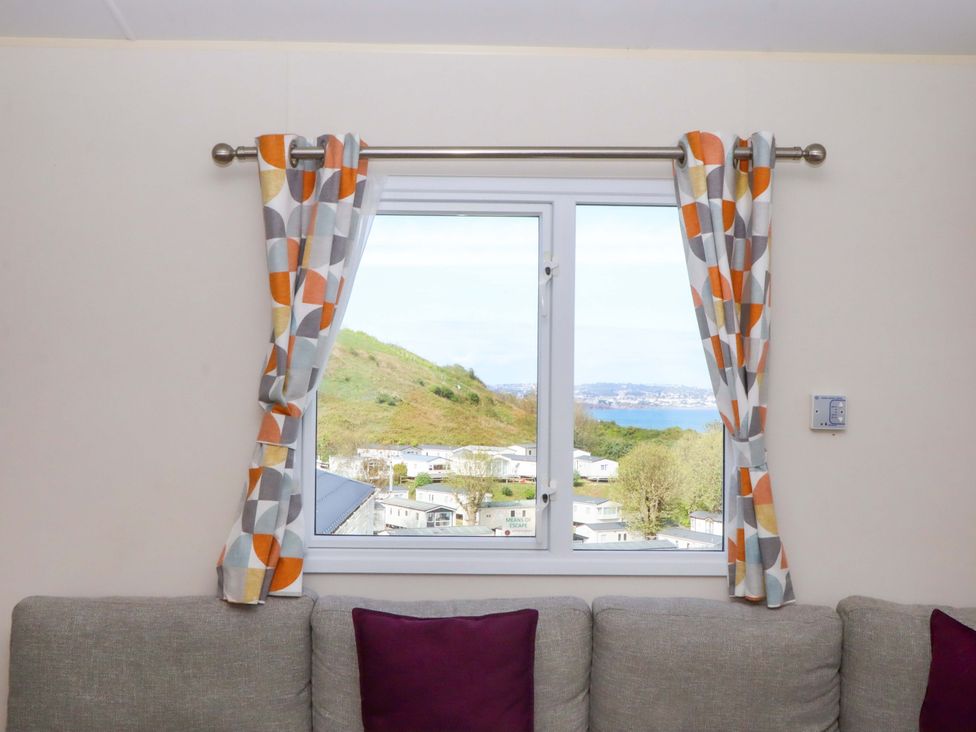 A window with curtains near a sofa at 213 Seaview Caravan