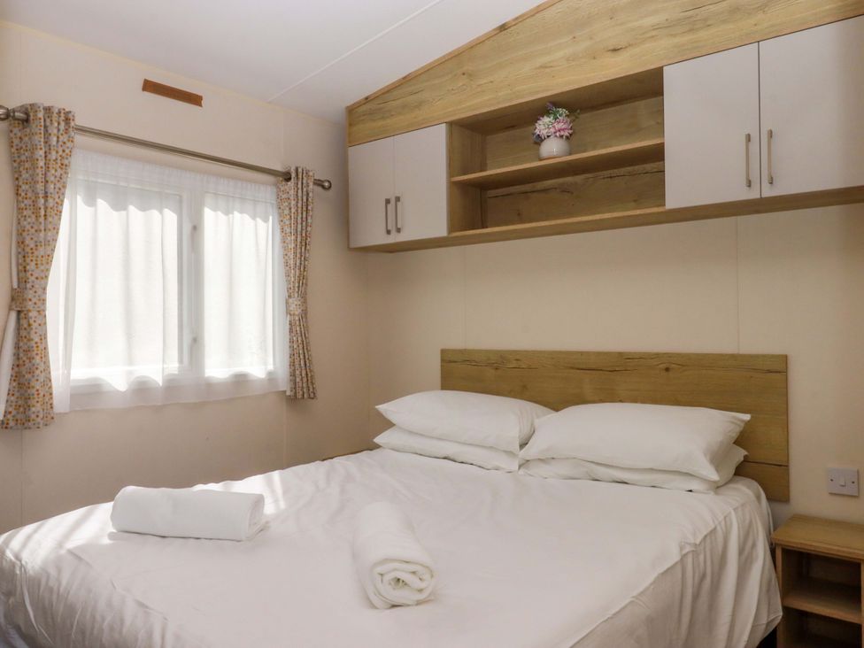 A bedroom with a bed and window at 213 Seaview Caravan in 