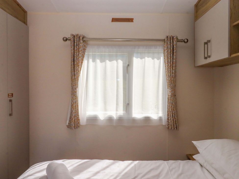 A bedroom with a window and curtains at 213 Seaview Caravan