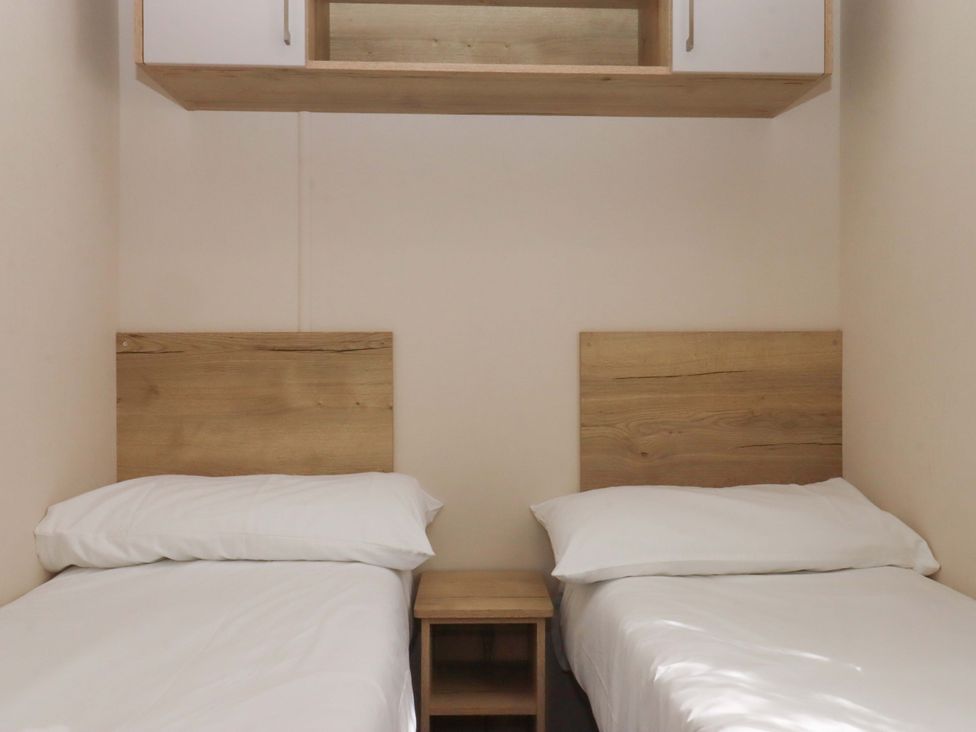 A bedroom with two single beds and a nightstand at 213 Seaview Caravan