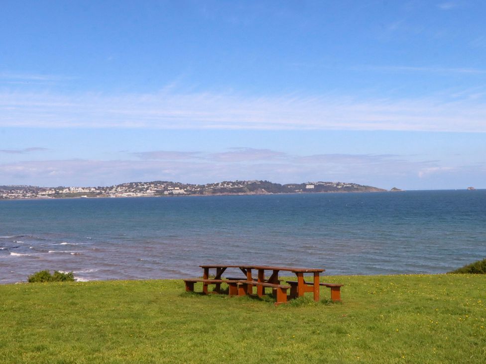 A picnic table on grass overlooking the ocean at 213 Seaview Caravan