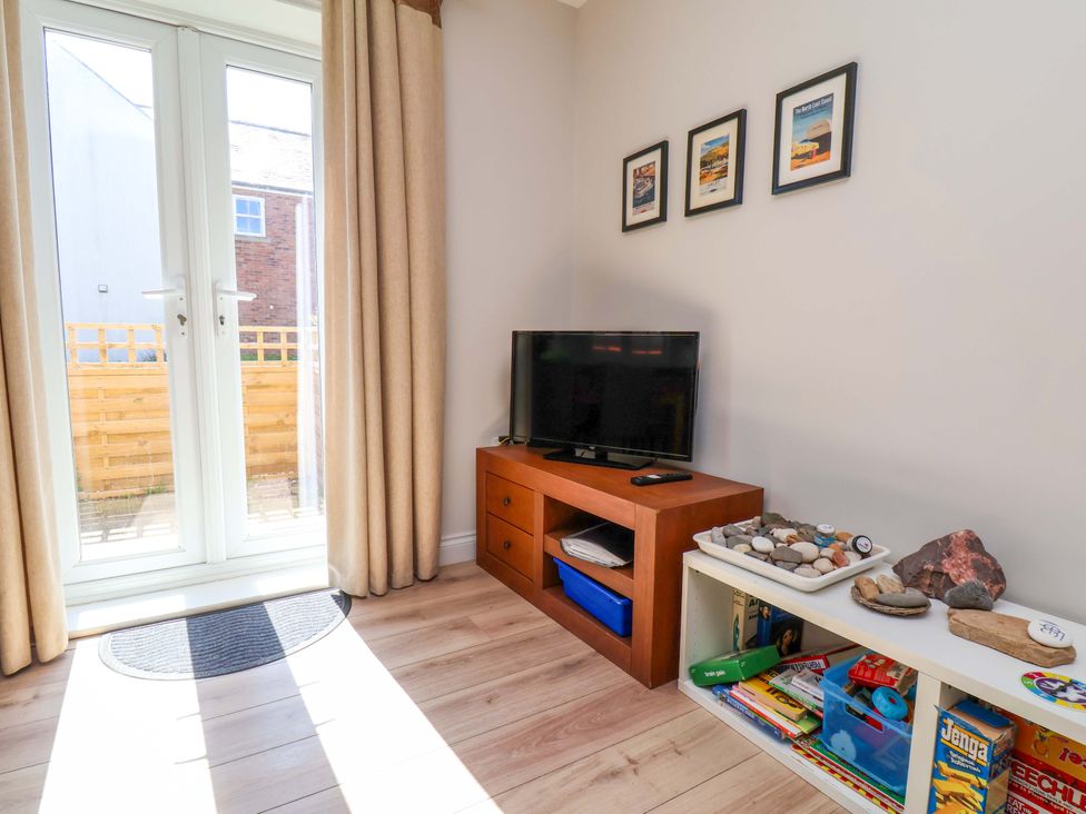 A living room with sliding doors and a television at Driftwood in Filey