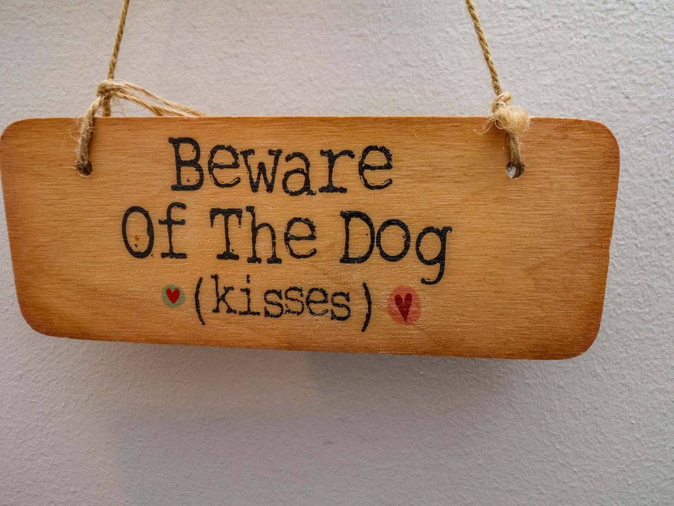 A wooden sign with the text 'Beware Of The Dog (kisses)'