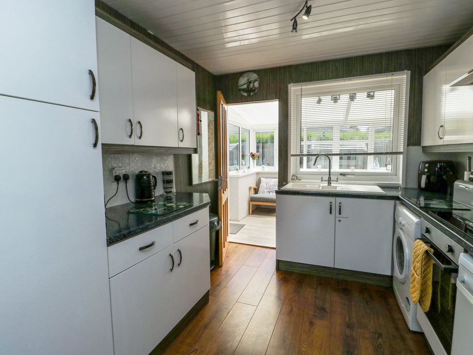 A kitchen with cabinets and appliances at Fern Hill Cottage Newborough
