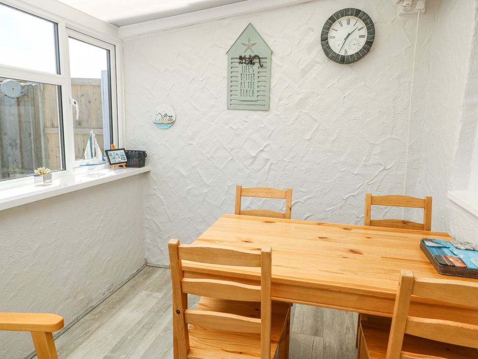 A dining room with a wooden table and chairs at Fern Hill Cottage Newborough