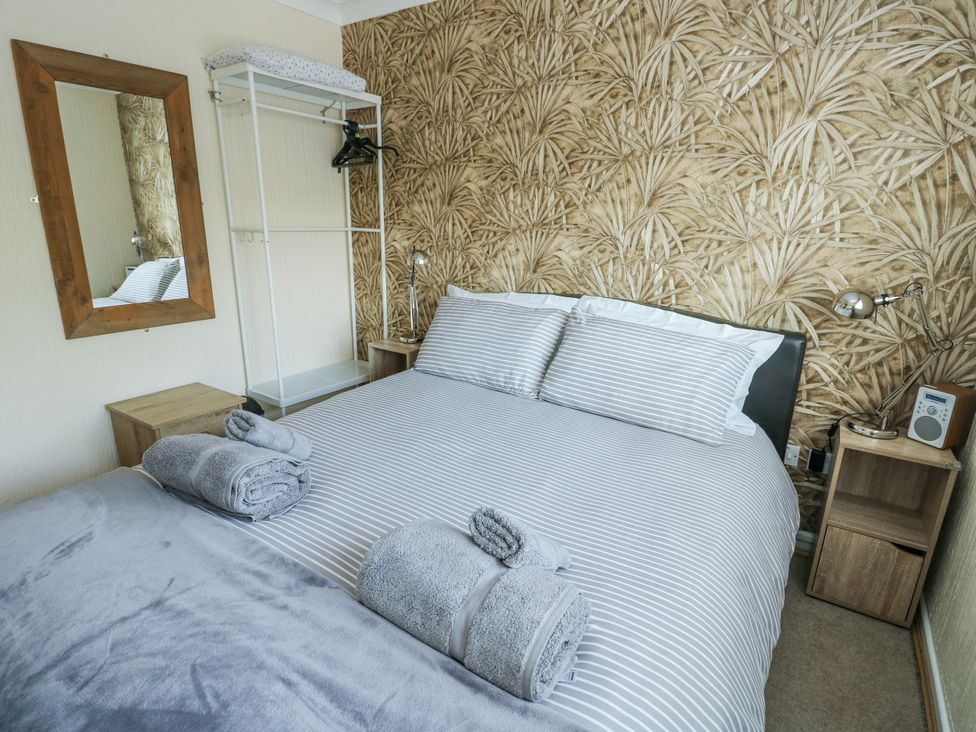 A bedroom with a bed and a mirror at Fern Hill Cottage Newborough