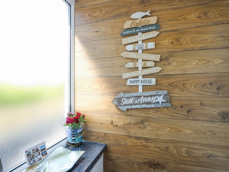 An entryway with decorative signs and a plant at Fern Hill Cottage in Newborough