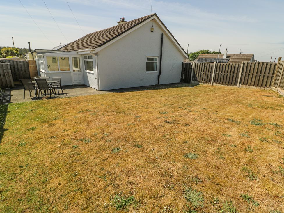 A garden with a house and patio furniture at Fern Hill Cottage Newborough